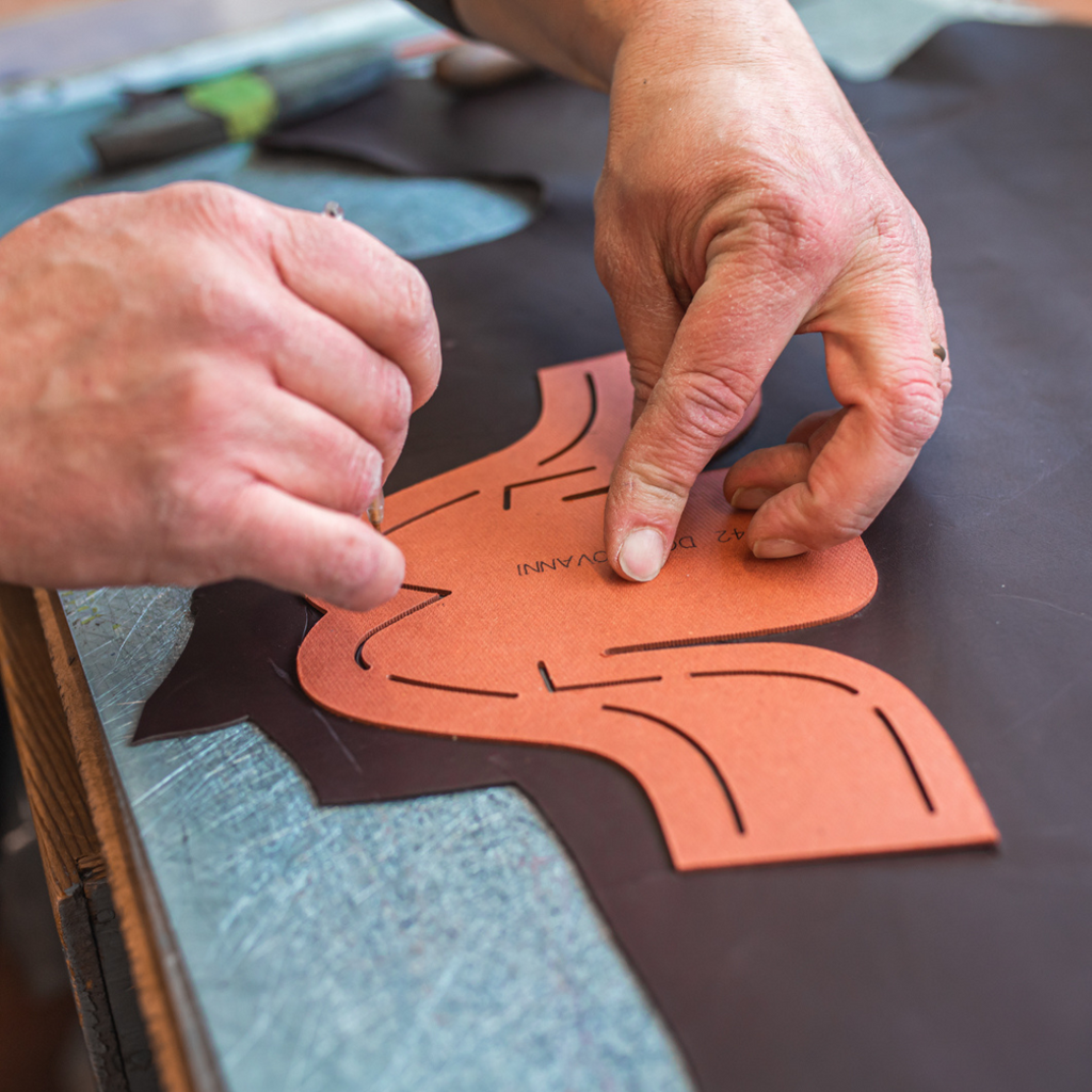 Artisan in Italy cutting the leather to make wingtip dress sneakers