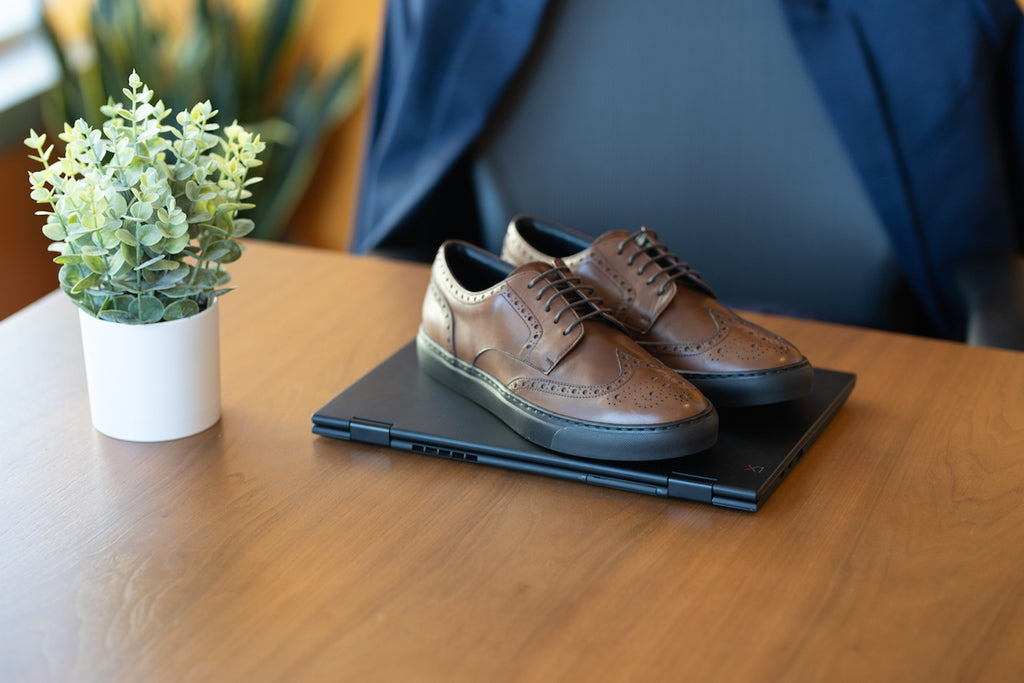 Brown leather sneakers with laptop in conference room