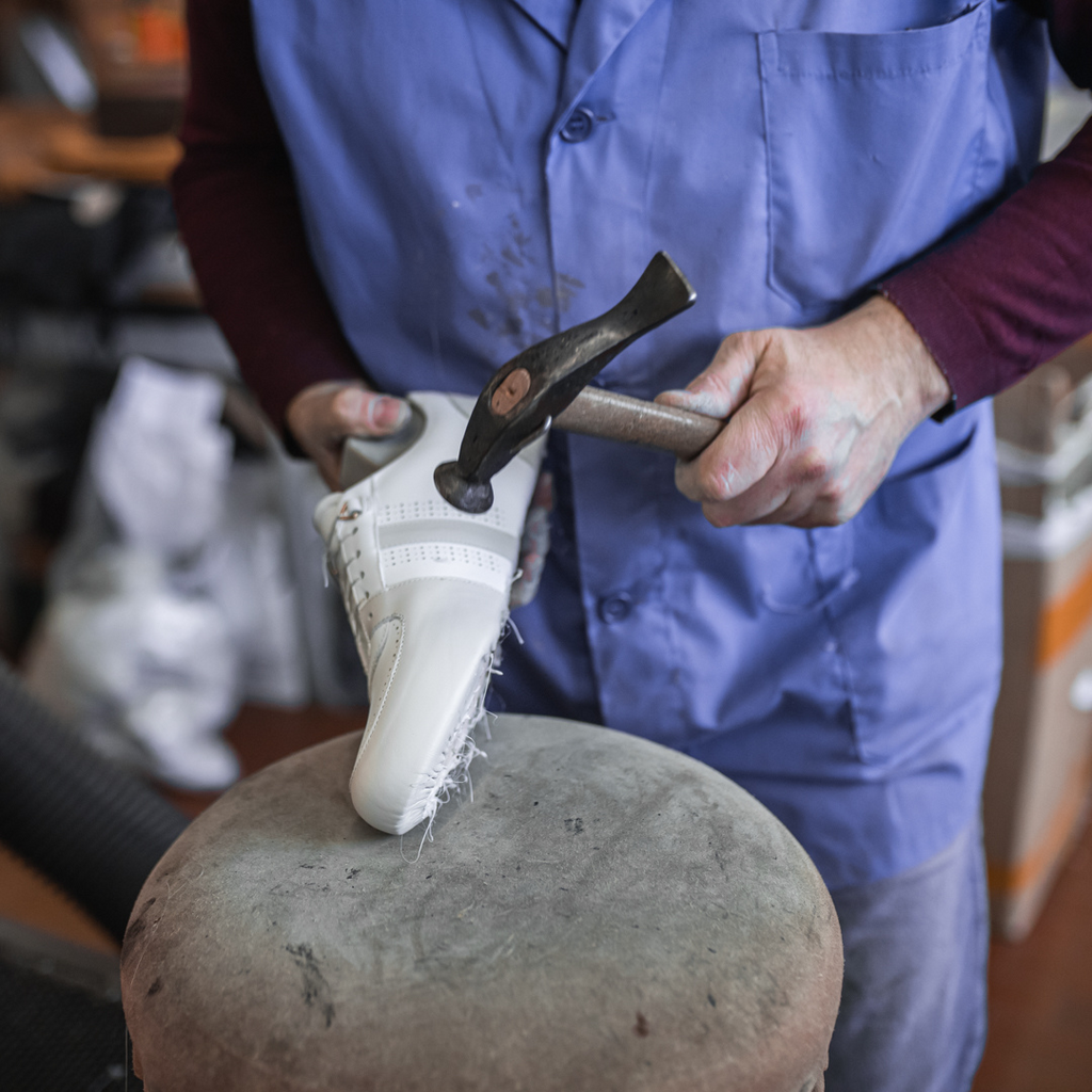 Artisan in Italy making women's white leather sneakers with beige, ivory gray accents