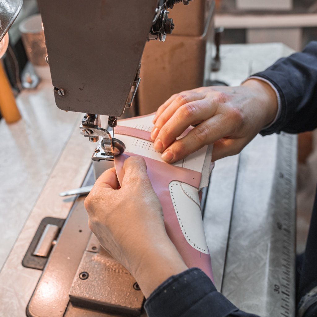 Artisan in Italy making women's white leather sneakers with pink accents