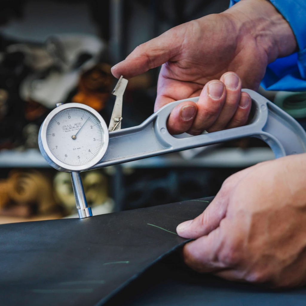 Artisan in Italy measuring black leather for dress sneakers
