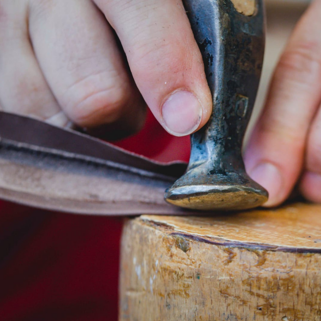 Artisan in Italy hammering brown leather for dress sneakers