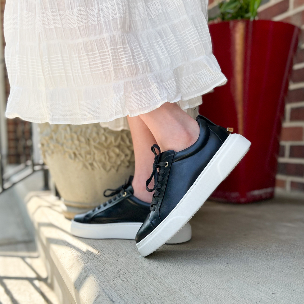 Woman wearing black sneakers with white skirt