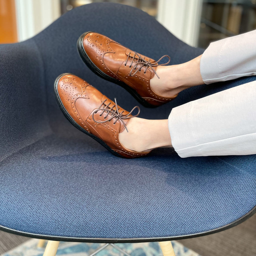 Woman wearing brown sneakers comfortably in office chair